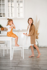 Two sisters play in a bright, stylish kitchen. Beautiful interior.