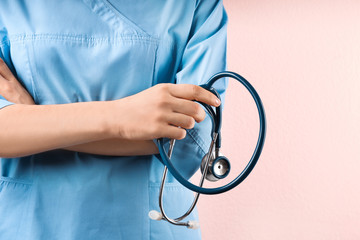 Doctor with stethoscope on pink background, closeup. Medical service