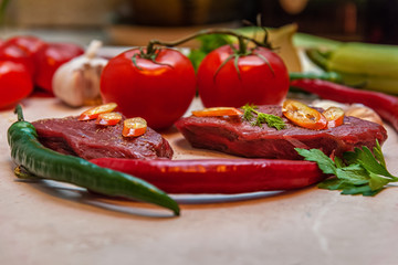 fresh raw beef steaks and vegetables on a table in the kitchen