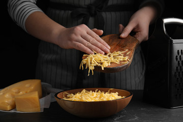 Woman with grated cheese at table, closeup
