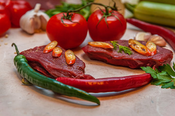 fresh raw beef steaks and vegetables on a table in the kitchen