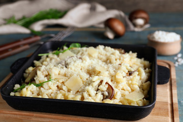 Delicious risotto with cheese and mushrooms on wooden board, closeup