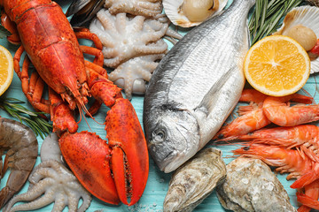Fresh fish and different seafood on blue wooden table, flat lay