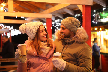 Obraz na płótnie Canvas Happy couple with drinks at Christmas fair