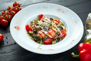 Tasty Nicoise Salad served white bowl on dark background with ingridients. Close up view on salad with arugula, quail eggs, tomatoes and salmon