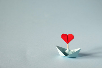 Valentine's day greeting card. Origami boat with heart flag on glitter blue background Romantic,...