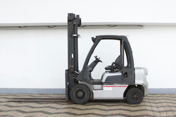 empty white forklift is on the background of a white wall on the street