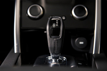 Interior of luxury suv car with black leather steering wheel and automatic shift gear.