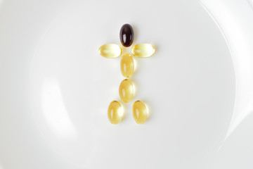 Fish oil and astaxanthin capsules on a plate in a human shape.