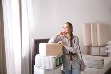 Young woman choosing mattress in furniture store