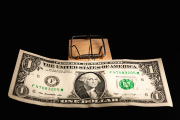 Dollar in a mousetrap on a black background. The bait in the form of money.