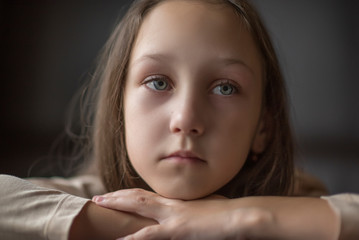 Dramatic portrait of a pensive girl against a dark background. 