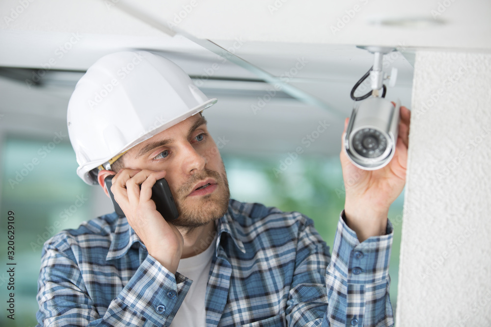 Wall mural contractor talking on telephone by cctv camera