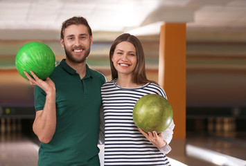 Young couple with balls in bowling club