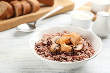Delicious brown rice in bowl on white wooden table