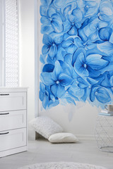 Stylish living room with blue flowers painted on wall. Floral pattern in interior design