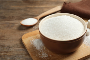Fototapeta na wymiar Granulated sugar in bowl on wooden table
