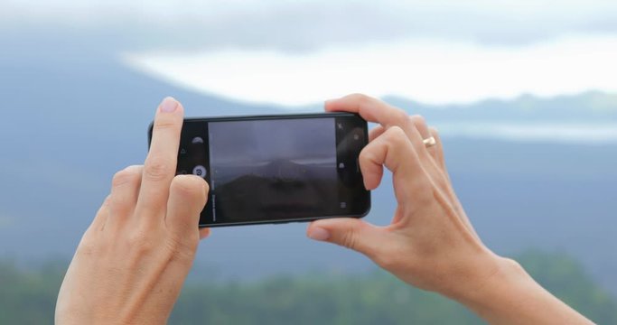 Close up shot of female hands taking a picture of cool volcano in jungles - always online, tourism concept 4k footage