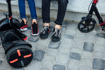 Couple legs near electric mini hoverboard in park. Close up leg photo.