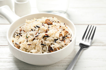 Delicious rice pilaf with mushrooms on white wooden table