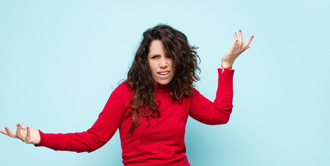 young pretty woman shrugging with a dumb, crazy, confused, puzzled expression, feeling annoyed and...