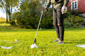 Young male volunteer picking up plastic from grass