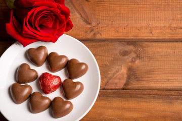 Valentine's Day, chocolate candy hearts on a  and a red rose