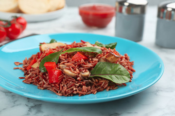 Tasty brown rice with vegetables on white marble table, closeup