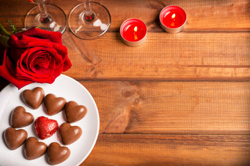 Valentine's Day, chocolate candy hearts, red rose, candles, glasses