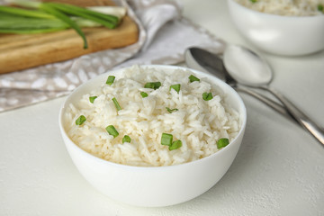 Bowl with tasty cooked rice on white table