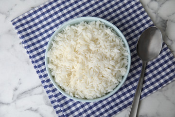 Bowl with tasty cooked rice on marble table, flat lay