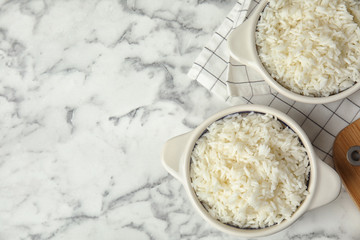 Bowls with tasty cooked rice on marble table, flat lay. Space for text