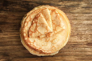 Stack of fresh thin pancakes on wooden table, top view