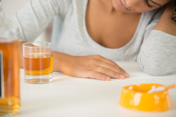 bottle with alcohol on table and drunk woman on background