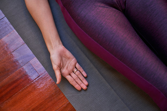 From above anonymous female in sportswear lying on floor in Corpse pose and resting during yoga workout at home