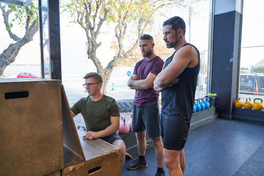 Personal trainer in gym giving directions to two boys to do multifunctional training