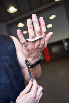 Strong man prepares to exercise in the gym with magnesium in his hands. Young athlete practicing multidisciplinary training