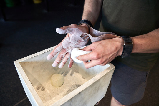 Strong man prepares to exercise in the gym with magnesium in his hands. Young athlete practicing multidisciplinary training