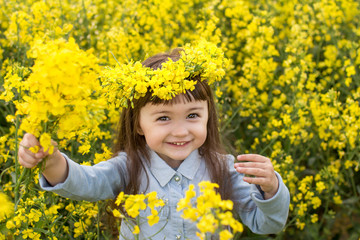 a little girl in a field of flowering yellow rapeseed. rapeseed field. girl with yellow flowers