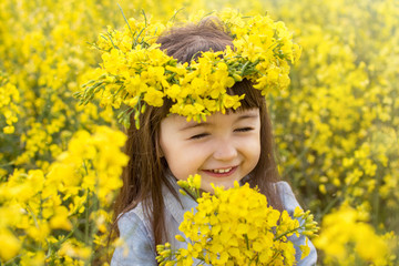 a little girl in a field of flowering yellow rapeseed. rapeseed field. girl with yellow flowers