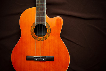 Six-string acoustic guitar on a dark brown background. Classical Spanish guitar. Musical...