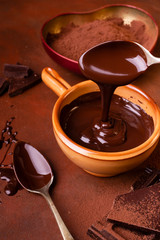 brown background, smeared with cocoa and chocolate chips, some pieces of chocolate and a bowl with...