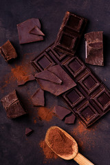 wooden spoon with cocoa powder and pieces of dark chocolate.