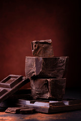 in the foreground stacked pieces of dark chocolate sprinkled with cocoa powder.
