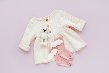 White dress with pink socks and toy bear. Set of baby clothes and accessories for spring  or summer...