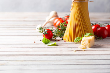 Pasta spaghetti, olive oil, tomato and other products for cooking on wooden table. Space for text.