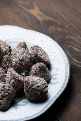 Chocolate candies in coconut shavings on a saucer on a wooden background, selective focus