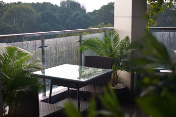 Photo of the table and two chairs on a cozy balcony with view on the rainy nature