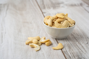 Cashew nuts in the white bowl on wood table