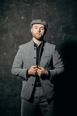 Ready for business. A bearded man in a cap and a gray suit fastens his jacket.